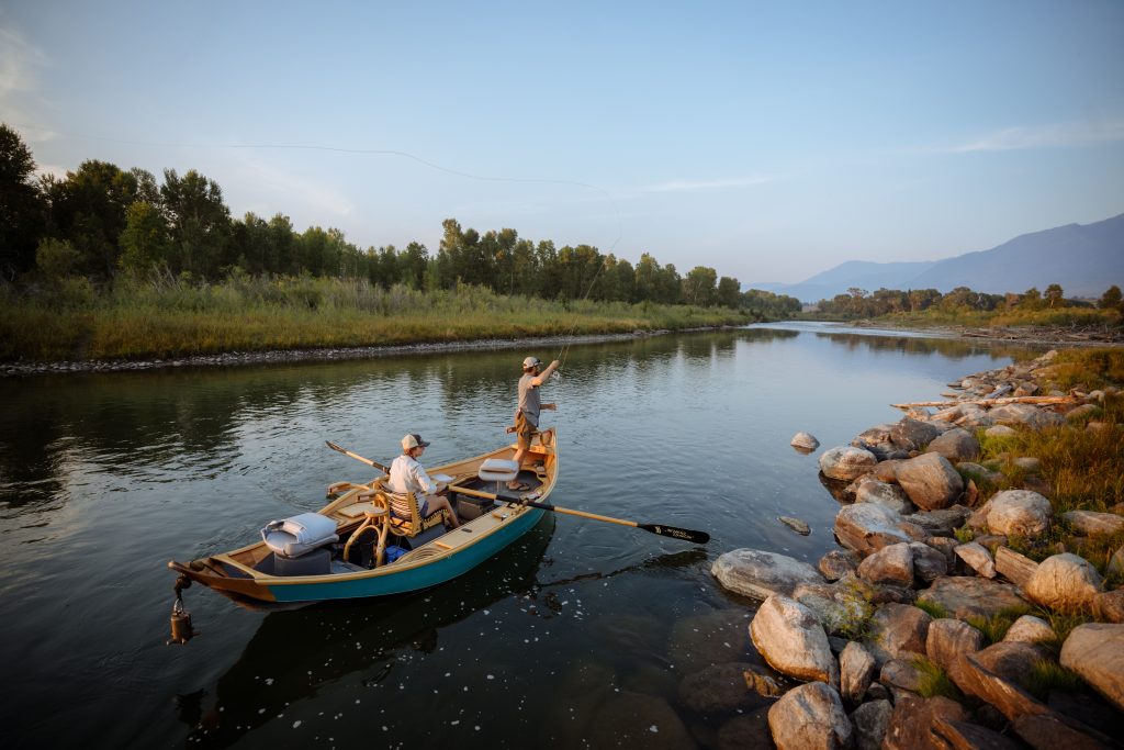 A man and a woman paddle on a river in custom Cajune boat