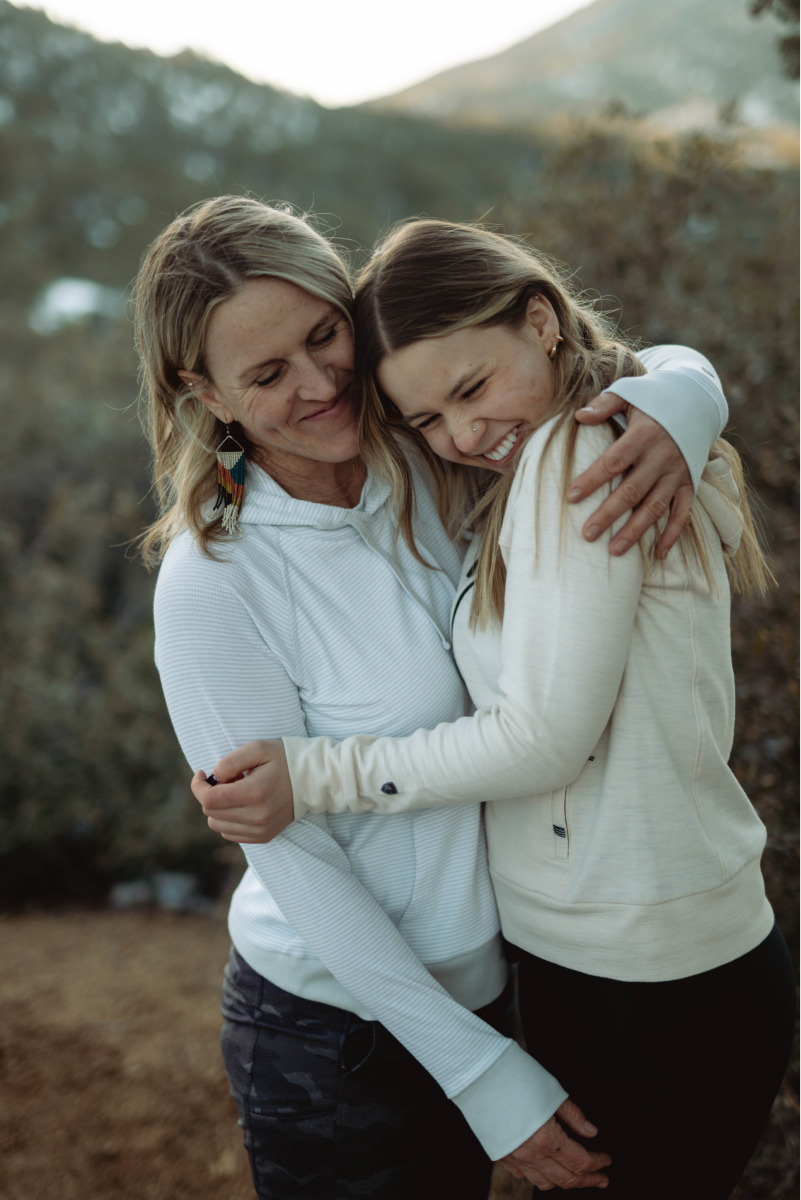 Mom embracing her daughter in the backcountry both dressed in women's KUHL clothing.