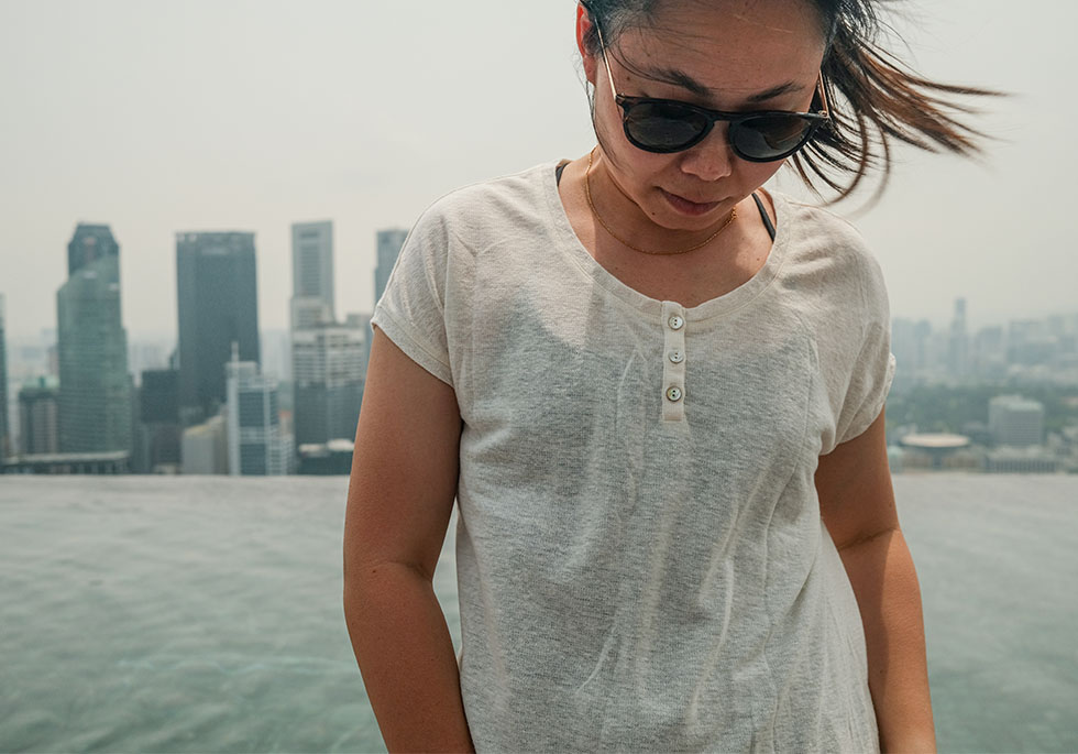 Maggie standing in KUHL women's summer clothing next to a pool that overlooks Singapore