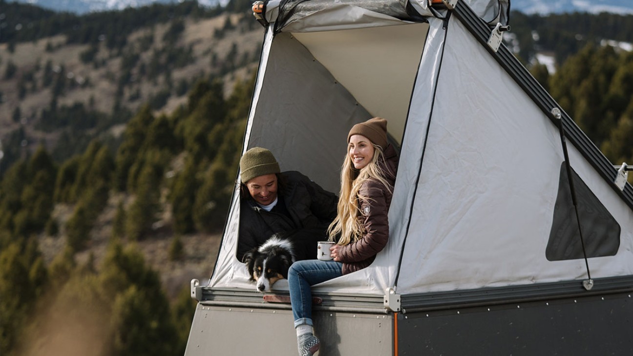 A man and a women in KUHL clothing enjoying camping in a rooftop tent