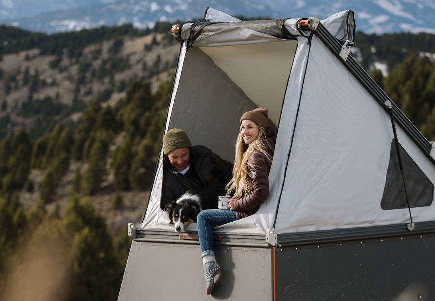 A man and a women in KUHL clothing enjoying camping in a rooftop tent