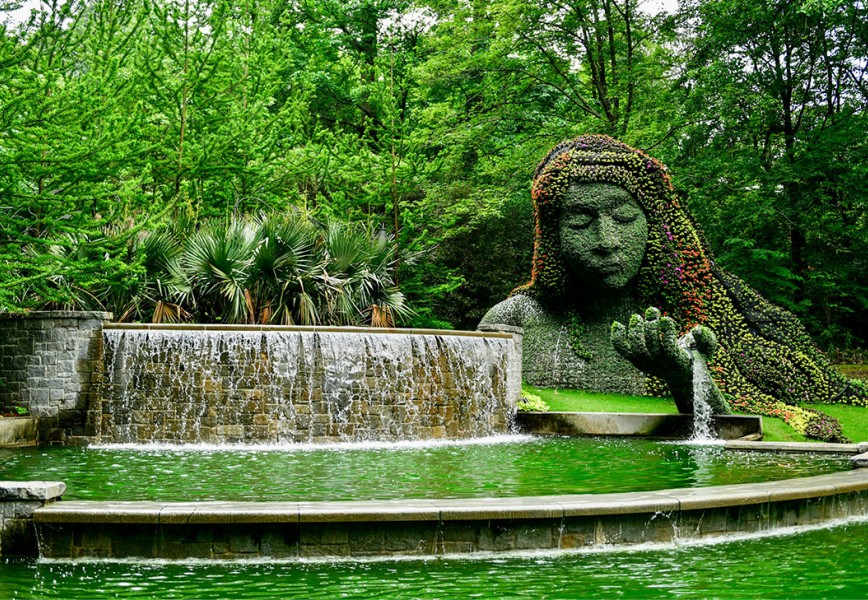 The image shows the iconic Earth Goddess (sometimes called "Mother Earth" or "Gaia"), a massive 25-foot-tall living plant sculpture in the Cascades Garden.