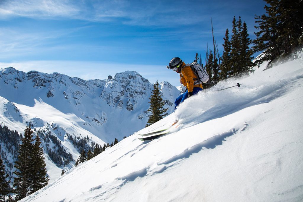 Man Skiing Down The Mountain In Yellow Jacket During The Day