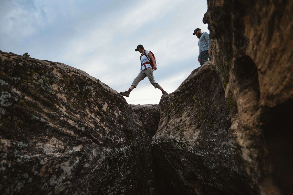 woman hiking on rocks while man watches