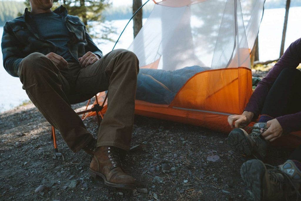 man sitting next to the orange tent