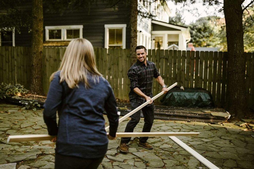 man and woman holding plunks in the backyard