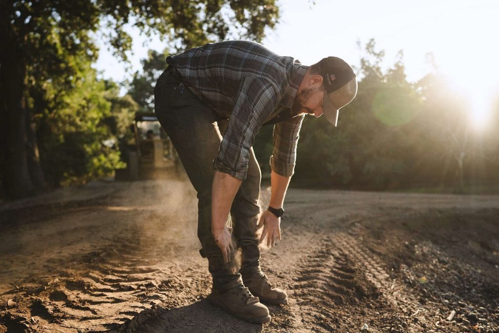 man cleaning dirt from pants