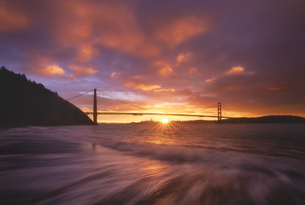 bridge on the body of water in the yellow and purple sky