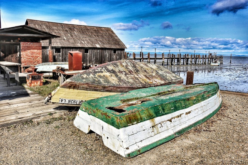 white and green boat turned upside down on the gray dock