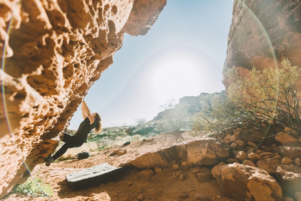 woman in KÜHL leggings climbing on red rock