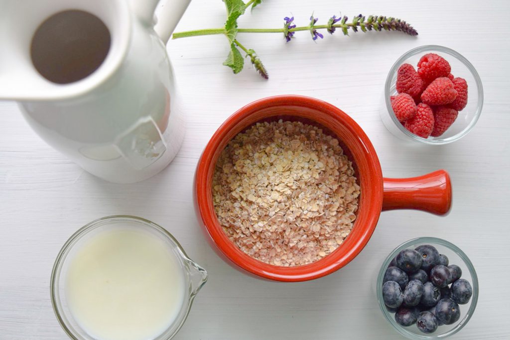 white picther almond milk oatmeal and berries on table