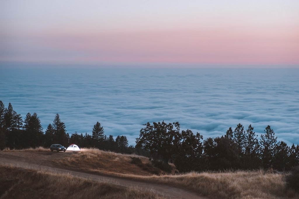 car and tent next to a lake and dirt road