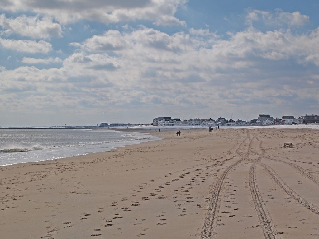 long sand beach with houses in the distance