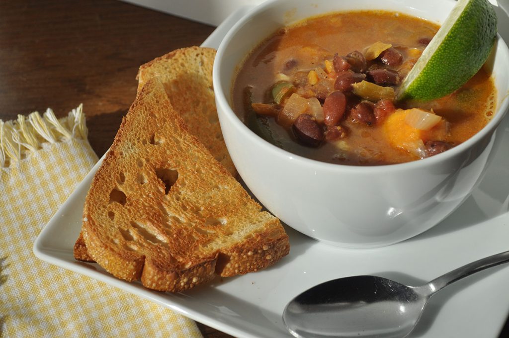 white bowl with brown stew and slice of bread on the side