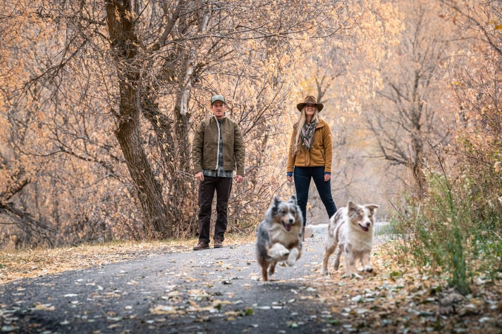 man and woman in KÜHL jackets watching two dogs