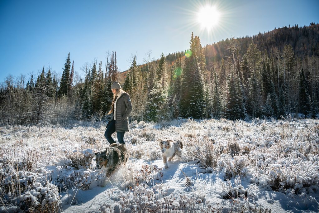 woman in KUHL parka with dog on snowy field