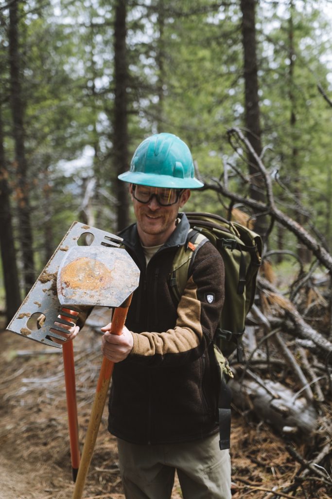 Glenn picking the right tool for the job to build a mountain biking trail in KUHL clothing for me