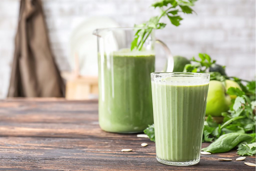 Glass and jug of healthy smoothie on table