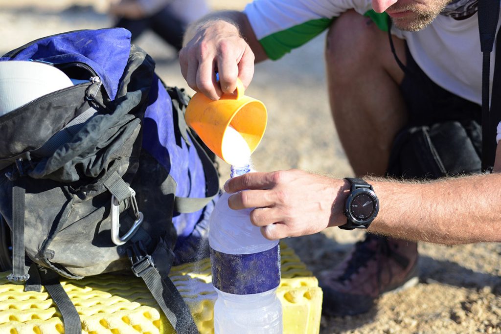 Adventure man pouring Hydration Electrolyte Powder in water bottle