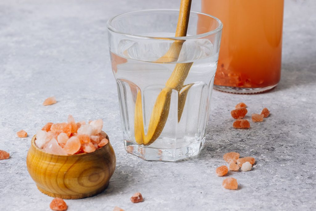 water in a glass and Himalayan salt isolated on white background